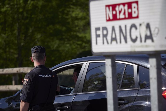Un cartell assenyala la direcció a Frana mentre un policia interroga a un conductor en un control a la frontera navarrs-francesa.