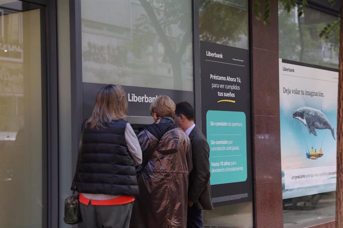 Tres personas efectúan una operación en un cajero de una oficina de Liberbank, que ha convocado a los sindicatos para negociar un nuevo Expediente de Regulación de Empleo (ERE), en Madrid, a 21 de octubre de 2019.