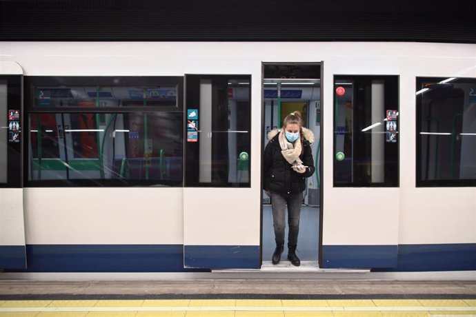 Una mujer protegida con mascarilla se baja de uno de los metros de la capital en un andén con círculos rojos en el suelo que Metro de Madrid ha colocado en sus estaciones para establecer distancia de seguridad entre viajeros ante la pandemia del Covid-1
