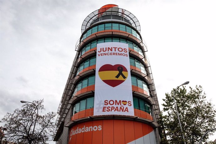 Ciudadanos despliega una lona con un crespón negro junto a la bandera de España en su sede nacional.