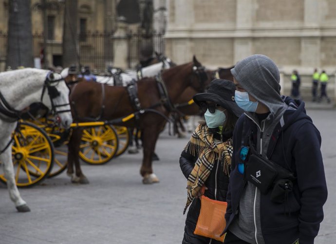 Impacto del coronavirus en el sector turístico . Dos turistas con mascarillas pasean por el centro de Sevilla (Andalucía, España).