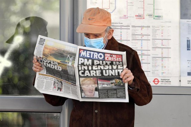Hombre con mascarilla leyendo un periódico con la noticia del ingreso de Boris Johnson en cuidados intensivos por el coronavirus en portada