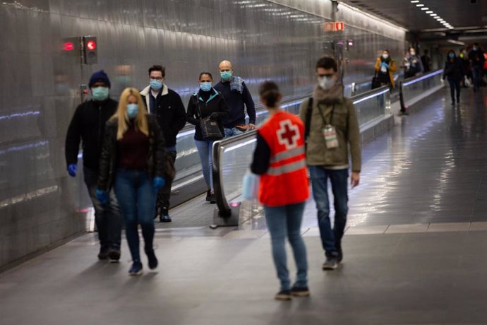 Una voluntaria de Cruz Roja entrega mascarillas a los pasajeros en la estación catalana de Diagonal el día en el que se reactiva la actividad laboral no esencial en Cataluña, en Barcelona (Catalunya, España), a 14 de abril de 2020.