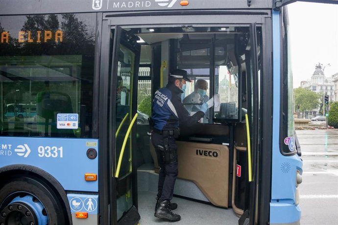 Un agente de la Policía Municipal de Madrid reparte mascarillas a los pasajeros de un autobús de la línea 9 de la EMT 