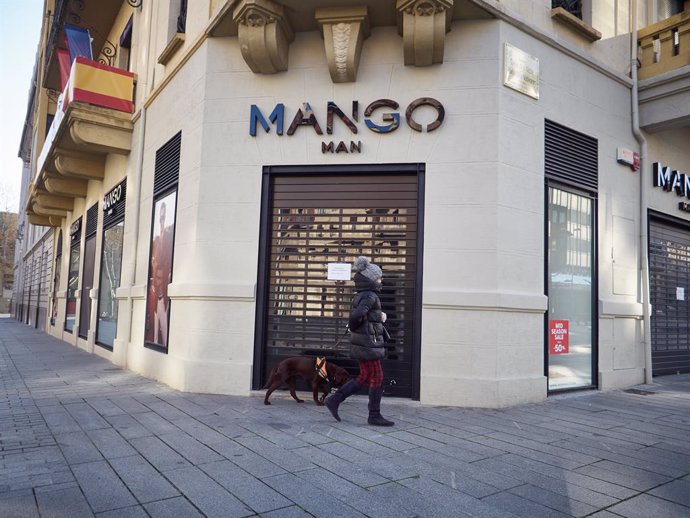 Una dona passeja al seu gos davant de la botiga PISPO tancada durant el terme de la segona setmana de confinament de l'estat d'alarma per coronavirus, covid-19. A Pamplona, Navarra (Espanya) a 29 de mar de 2020.