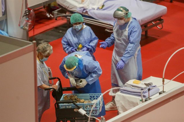 Personal sanitario ayudan a una paciente en el interior del hospital provisional de Ifema habilitado para personas con Covid-19.