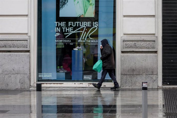 Una persona camina por una calle de Madrid donde las temperaturas han bajado estrepitosamente durante el segundo día de la entrada en vigor de la limitación total de movimientos salvo de los trabajadores de actividades esenciales, medida adoptada ayer p