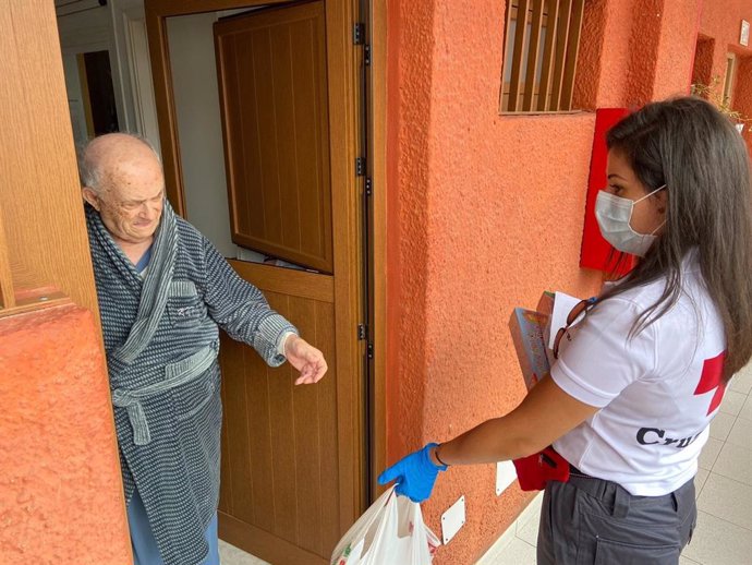 Una voluntaria de Cruz Roja presta ayuda a una persona mayor durante el estado de alarma