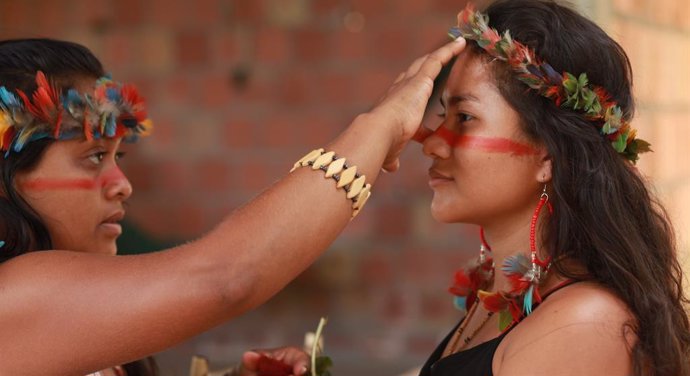 Dos mujeres indígenas se pintan la cara