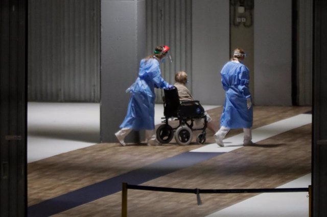Una sanitaria traslada a un paciente en silla de ruedas en el hospital de campaña de IFEMA.