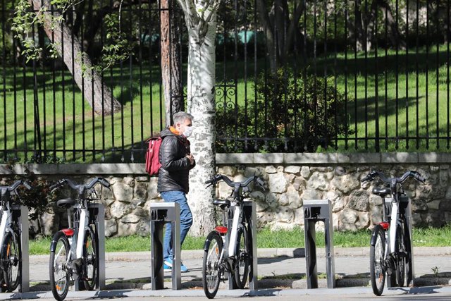 Un hombre pasa junto a bicicletas de BiciMAD en una estación ya preparadas