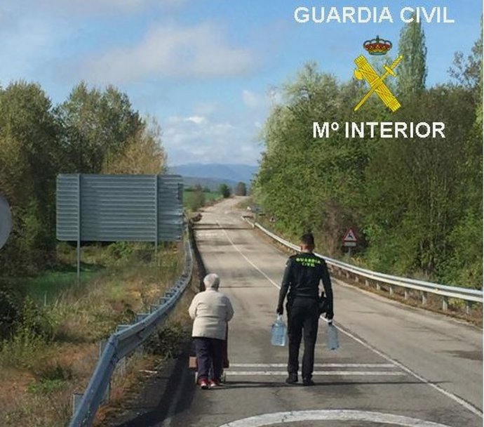 Un agente de la Guardia Civil ayuda a una mujer mayor a llevar la compra hasta su casa en Treviño (Burgos)