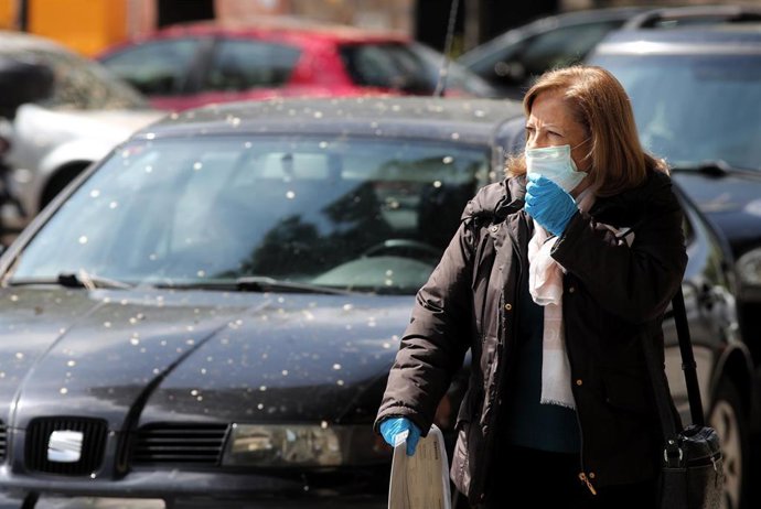 Una mujer protegida con mascarilla pasa junto al Palacio de Hielo.
