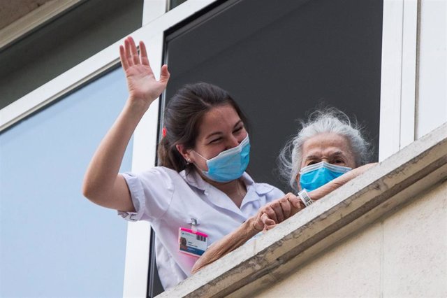 Una sanitaria ayuda a una paciente mayor a salir a la ventana para rendir homenaje a los sanitarios en el Hospital Fundación Jimenez Diaz durante la pandemia de Covid-19 en Abril 20, 2020 in Madrid, España