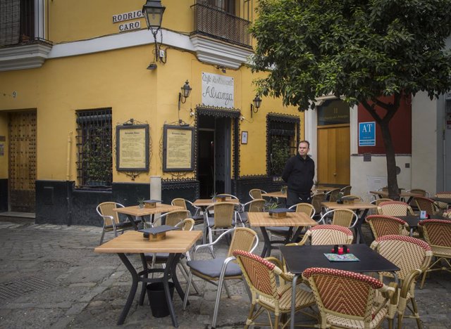 Un camarero espera la llegada de clientes en un restaurante del barrio de Santa Cruz en Sevilla (Andalucía, España)