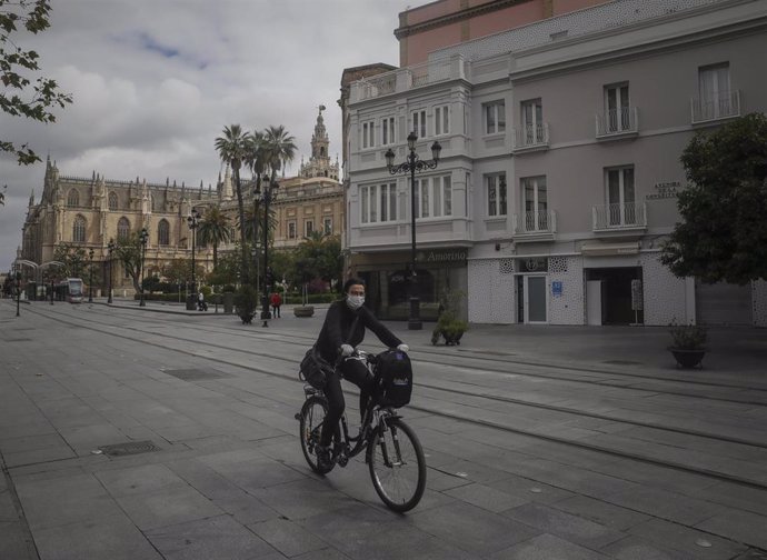 Una mujer protegida con mascarilla monta en bicicleta durante el estado de alarma en Sevilla