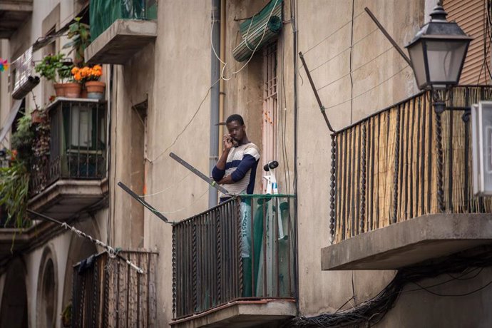 Un home parla per telfon al seu balcó durant el primer dia laborable de la segona setmana des que es va decretar l'estat d'alarma al país a conseqüncia del coronavirus, a Barcelona/Catalunya (Espanya) a 23 de mar de 2020.