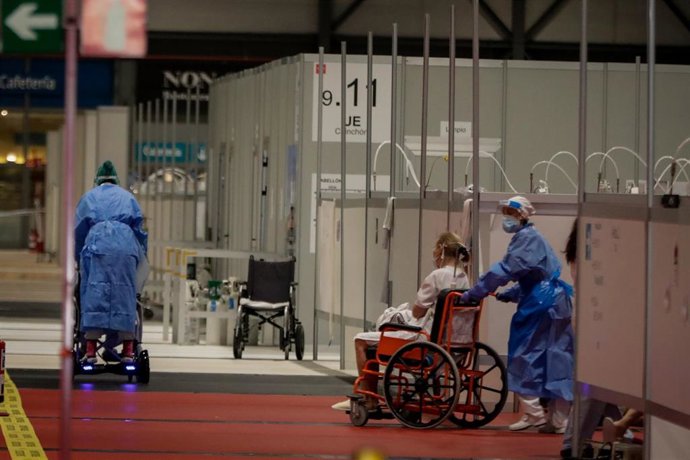 Dos sanitarios trabajan trasladando pacientes en silla de ruedas en el Pabellón 9 del hospital de campaña de Ifema.