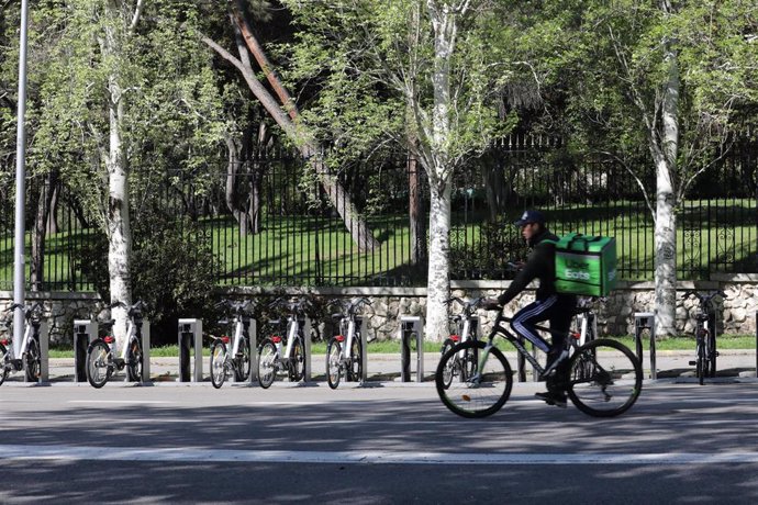 Un rider de Uber Eats pasa junto a bicicletas de BiciMAD 