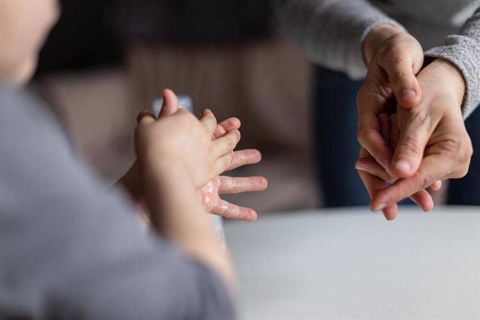 Una mujer y su hijo se desinfectan las manos.