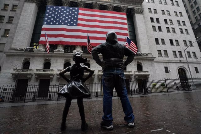 Un hombre junto a la estatua de la Niña sin miedo ante el edificio de la Bolsa en Nueva York