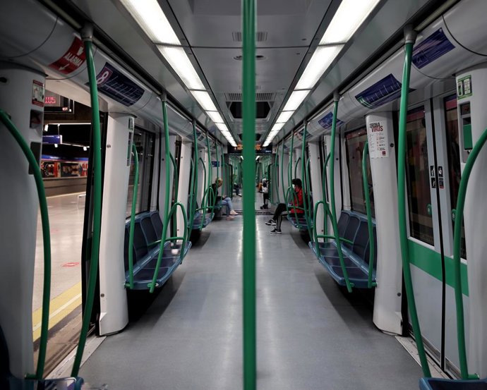 Vista general de un metro de la capital con pasajeros parado en un andén con círculos rojos en el suelo que Metro de Madrid ha colocado en sus estaciones para establecer distancia de seguridad entre viajeros ante la pandemia del Covid-19.
