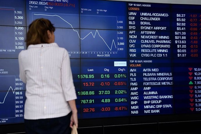 A woman looks at the digital market boards at the Australian Stock Exchange (ASX) in Sydney, Friday, March 13, 2020. The ASX has fallen nearly seven per cent on opening after Wall Street suffered its biggest drop since the Black Monday crash of 1987, wh