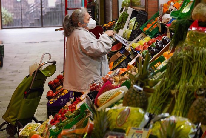 Una señora con mascarilla comprando en el mercado de Triana (Sevilla) en el tercer día de alarma. Sevilla a 17 de marzo del 2020