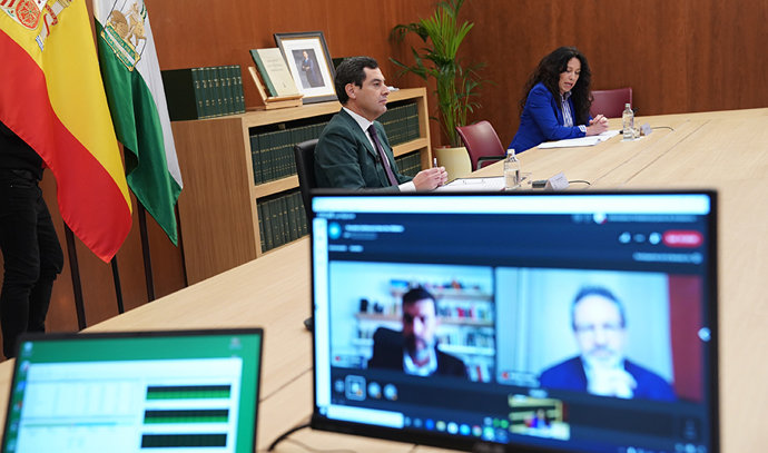 El presidente de la Junta, Juanma Moreno, y la consejera de Igualdad, Rocío Ruiz, durante la  videoconferencia celebrada este miércoles con Save the Children. 