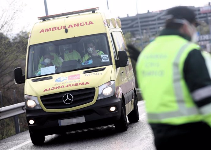 Sanitarios del SUMMA 112 de la Comunidad de Madrid totalmente protegidos conducen una ambulancia que se dirige a la entrada del recinto de IFEMA.