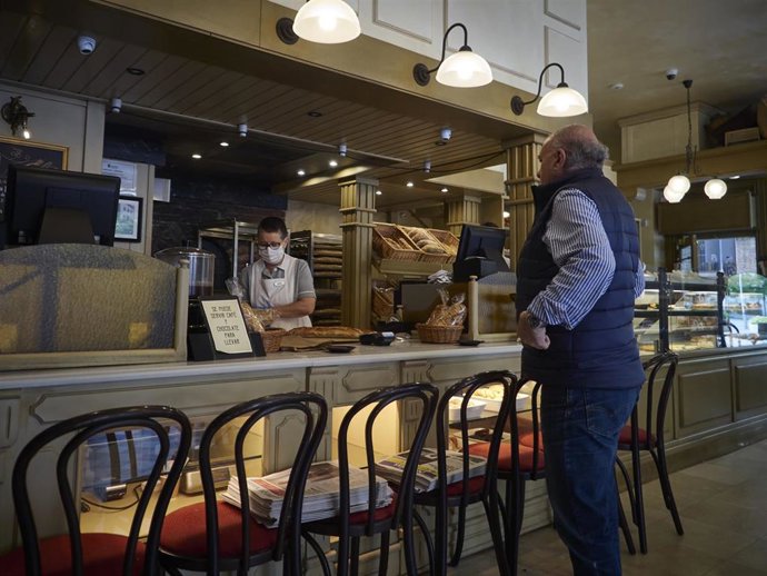 Un hombre compra pan en una panadería durante el día en el que se reactiva la actividad laboral no esencial en las empresas cuyos empleados no puedan teletrabajar cuando se cumple un mes desde el inicio del estado de alarma decretado a consecuencia del 
