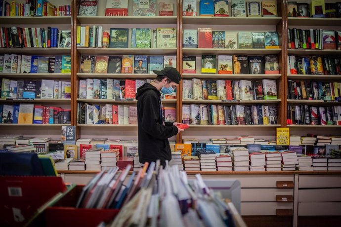 Un joven observa un libro de la papelería DEMOS, un colectivo que permanece cerrado por la pandemia del Covid-19 ya que solo están permitidas la aperturas de locales de primera necesidad, aunque determinados centros, durante el día de hoy sí permanecen 