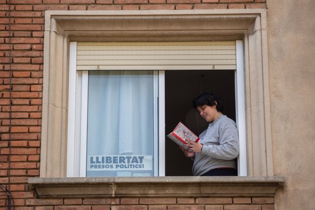 Una joven lee un libro en el balcón de su casa con ocasión de la Diada de Sant Jordi,, en Barcelona / Catalunya (España), a 23 de abril de 2020.
