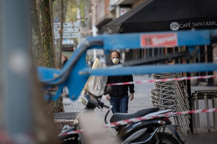 Un hombre protegido con una mascarilla camina cerca de una obra durante el noveno día laborable desde que se decretó el estado de alarma en el país a consecuencia del coronavirus, en Barcelona/Catalunya (España) a 26 de marzo de 2020.