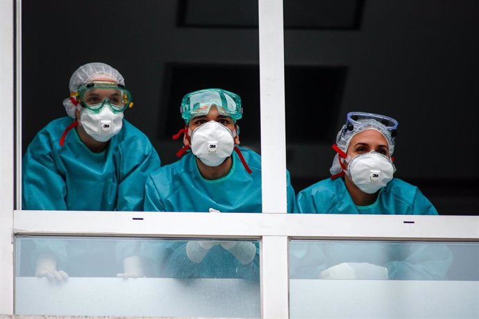 Varios sanitarios con protección EPI, mascarillas, gafas y guantes, observan desde la ventana el homenaje a los Sanitarios celebrado en el Hospital Fundación Jiménez Díaz durante la pandemia de Covid-19 en Abril 21, 2020 in Madrid, España