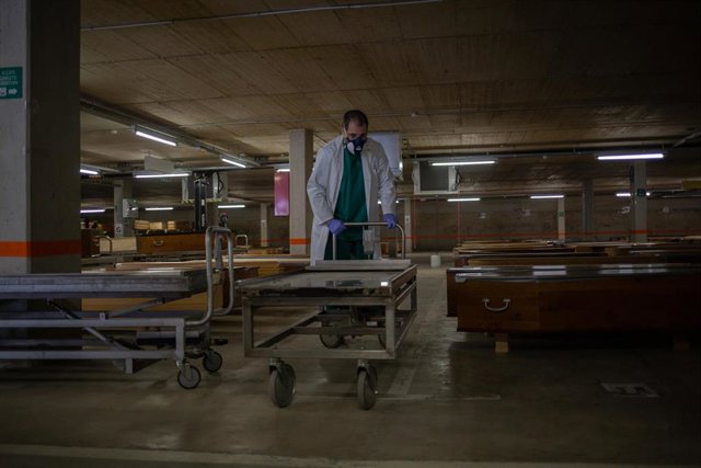 Un trabajador protegido con guantes y mascarilla en el tanatorio de campaña de Collserola en Barcelona