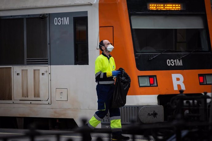 Un trabajador de la limpieza trabaja protegido con una mascarilla junto a un tren durante el segundo día laborable del estado de alarma por el coronavirus, en Barcelona/Catalunya (España), a 17 de marzo de 2020.