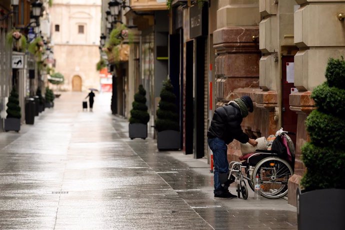 Una persona junto a una silla de ruedas en la calle Platería, vacía durante el estado de alarma, en Murcia (España) a 22 de marzo de 2020.