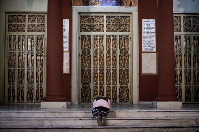 Una mujer reza junto a una iglesia ortodoxa en Atenas