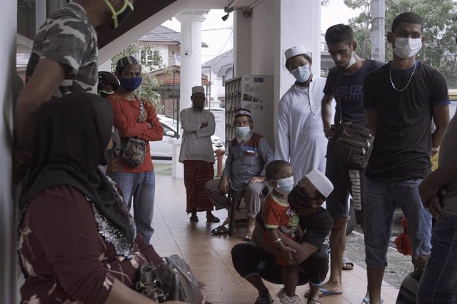 Un grupo de refugiados rohingya espera junto a una clínica de Kuala Lumpur