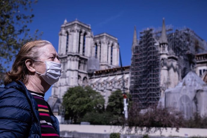 Una mujer con mascarilla pasa por delante de Notre Dame