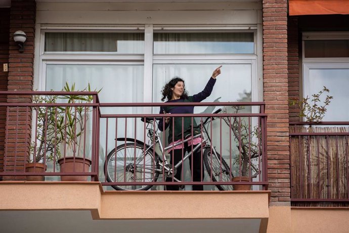 Una mujer con una bicicleta en el balcón de su casa durante el primer día laborable de la segunda semana desde que se decretó el estado de alarma en el país a consecuencia del coronavirus, en Barcelona/Catalunya (España) a 23 de marzo de 2020.