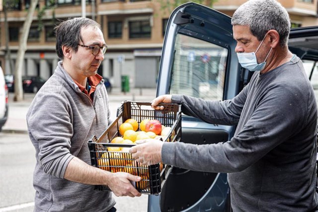 Un vecino de un edificio de la capital recibe una caja de alimentos de la huerta ecológica de Ecosecha 