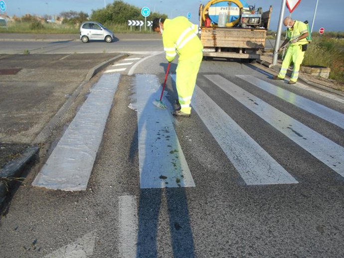 Un operario realiza labores de repinte de un paso de peatones en una travesía de Utrera (Sevilla)