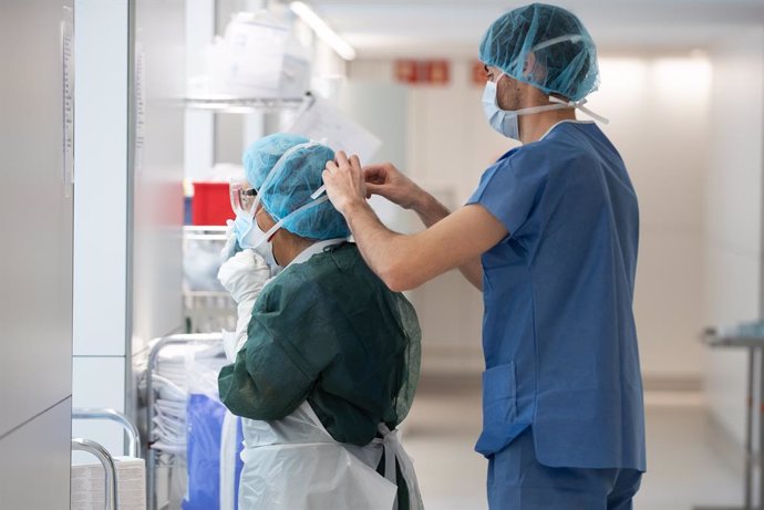Dos treballadors sanitaris es colloquen diversos elements de protecció davant el Covid-19 a l'Hospital Clínic de Barcelona, UCI d'atenció als pacients amb coronavirus, el 2 d'abril de 2020