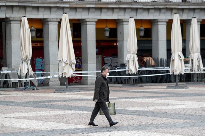 Un hombre con mascarilla anda por la Plaza Mayor