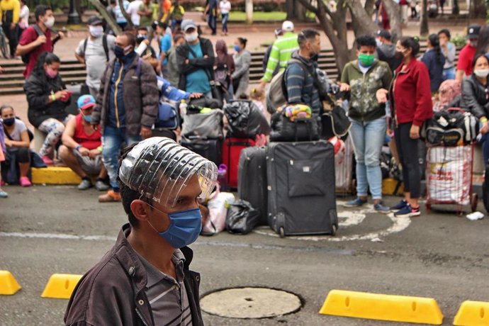 Migrantes venezolanos esperan un autobús que les lleve a la frontera en plena pandemia de coronavirus