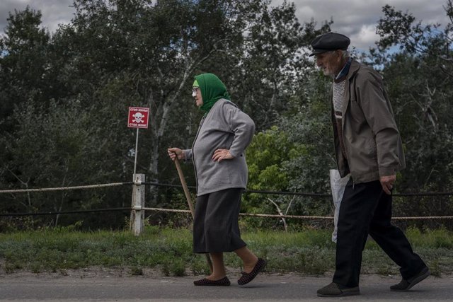 Una pareja de ancianos pasa junto a un campo minado en el este de Ucrania
