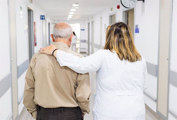 Un profesional sanitario acompaña a una persona mayor en un hospital