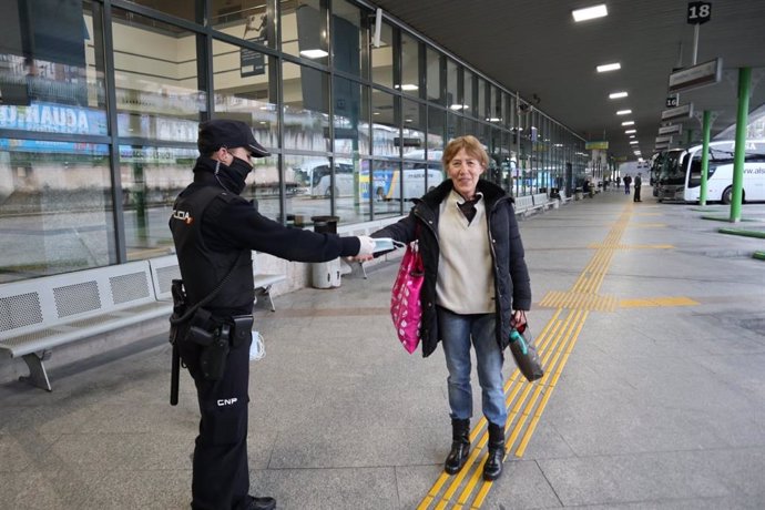 Un agente de la Policía Nacional entrega mascarillas en la estación de Oviedo,  13 de marzo de 2020.